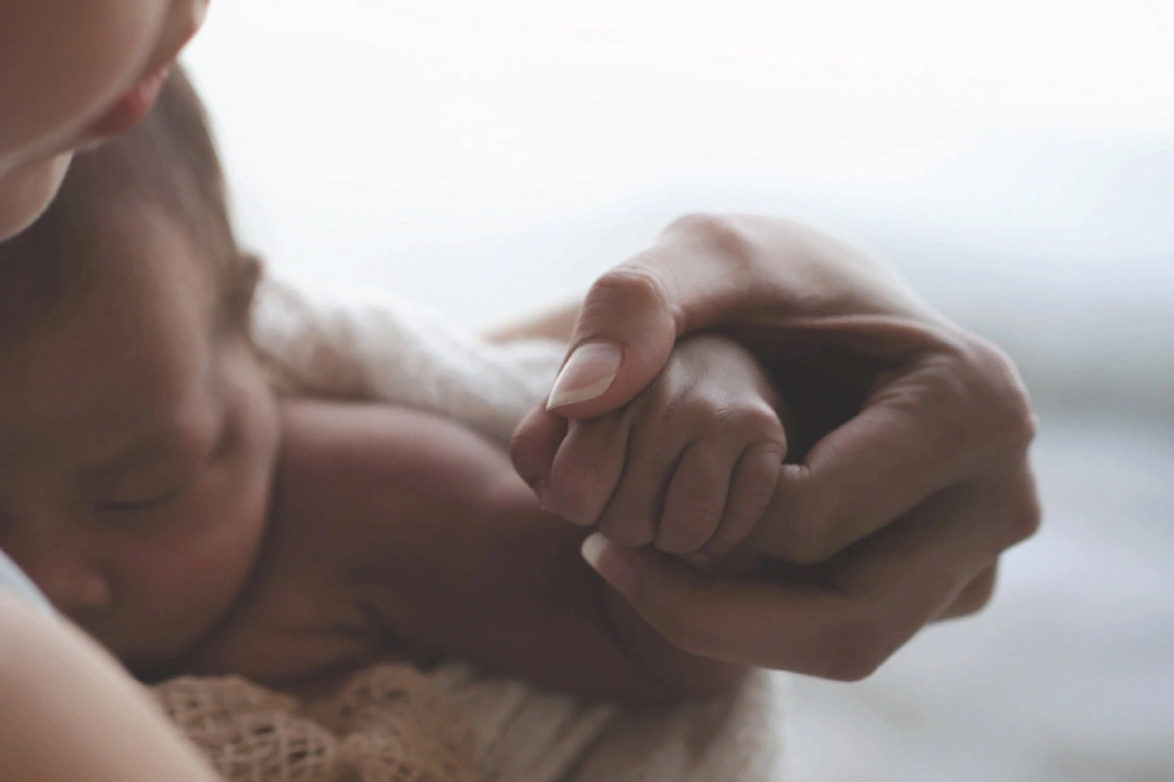 Mother and baby holding hands tightly